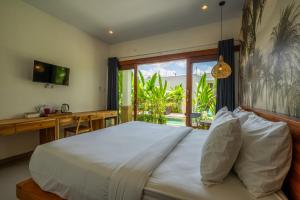 a bedroom with a bed and a desk and a window at Maha Prana Kedungu by Aayan in Tanah Lot