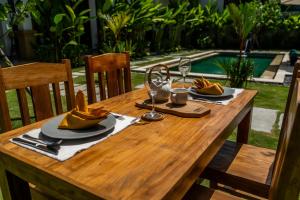 a wooden table with plates of food and wine glasses at Maha Prana Kedungu by Aayan in Tanah Lot