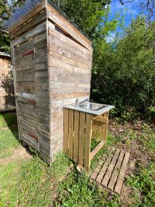 a wooden out house with a sink in the grass at CabaNomade in Hôpital-Camfrout