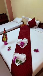 two beds in a hotel room with flowers on them at Hotel Shubham in Karīmnagar