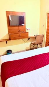 a bedroom with a bed and a desk with a tv at Hotel Shubham in Karīmnagar