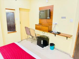 a room with a bed and a tv and a desk at Hotel Shubham in Karīmnagar