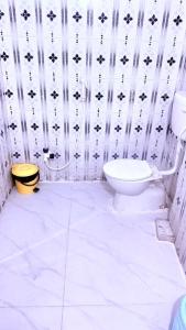 a bathroom with a white toilet and a black and white wallpaper at Hotel Shubham in Karīmnagar
