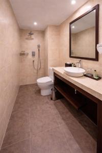 a bathroom with a toilet and a sink and a mirror at Hotel Presidency - Sosyo Circle in Surat