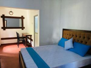 a bedroom with a bed with blue pillows and a table at Galeena Guest in Badulla