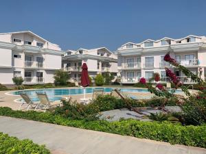 a large apartment complex with a swimming pool and chairs at Defne Beach Karya in Fethiye