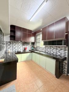a large kitchen with brown cabinets and tile floors at Kings Park Homestay in Ipoh