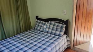 a bed with a blue and white comforter in a bedroom at Cabana in Santo Antônio do Pinhal