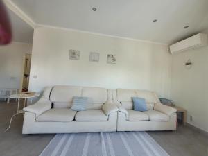 a white couch in a living room with blue pillows at Oeiras Historic Bedrooms in Oeiras