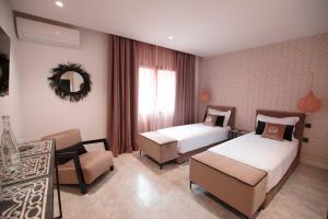 a hotel room with two beds and a chair at Riad La Petite Majorelle in Marrakesh