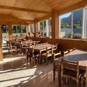 a dining room with tables and chairs and windows at Dogurashi Turbaza in Tsʼageri