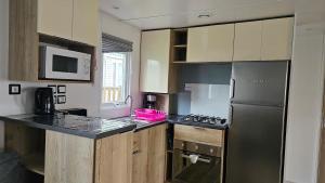 a kitchen with a black refrigerator and a microwave at Mobilhome Normandie in Litteau