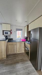 a kitchen with wooden cabinets and a stainless steel refrigerator at Mobilhome Normandie in Litteau