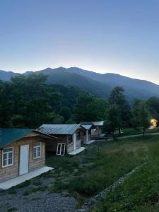 a group of houses in a field with mountains in the background at Dogurashi Turbaza in Tsʼageri
