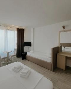 a bedroom with two beds and a desk and a mirror at Hotel Restaurant Univers Shiroke in Shirokë