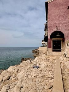 a building on the rocks next to the ocean at Golden View - Old town apartment in Rovinj