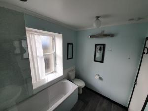 a bathroom with a bath tub and a window at Spacious 2 Double Bedroom House Wick Harbour in Wick +1 photo