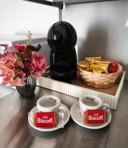 a counter with two cups and a coffee maker and flowers at Dimora Tarantina in Taranto +61 photos