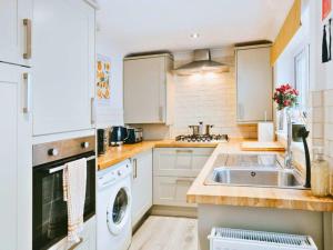 a kitchen with white cabinets and a sink at St Helens 3BR Home with Garden, Fast WiFi, Smart TV, Sleeps 6, Contractors & Long Stay Accommodation in Saint Helens