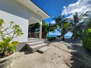 a white house on the beach with palm trees at Villa Admiral in Praslin