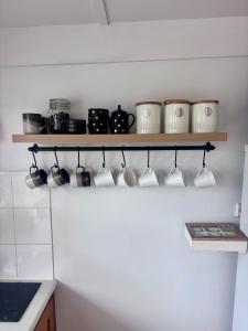 a kitchen with a shelf with pots and mugs at Pine Cottage in Dennes Point +20 photos