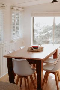 a dining room table with white chairs and a window at Pine Cottage in Dennes Point