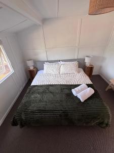 a bedroom with a large bed with two towels on it at Pine Cottage in Dennes Point