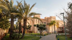 a building with palm trees in front of it at AG Hotel & Spa Marrakech in Marrakesh