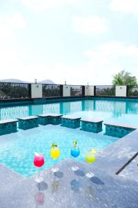 four wine glasses in front of a swimming pool at Pride Premier Alwar - Sariska in Alwar
