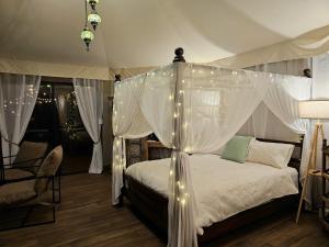 a bedroom with a canopy bed with lights on it at Clouds Serenity in Beechmont