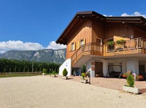 a house with a balcony and mountains in the background at Agritur Clementi in Nave San Rocco
