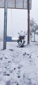 a motorcycle parked under a sign in the snow at Rara Sunrise Hotel in Chautha