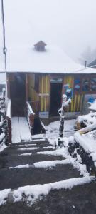 a building with snow on the ground in front of it at Rara Sunrise Hotel in Chautha