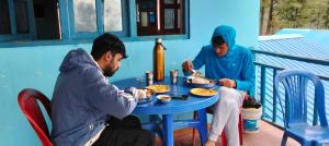 two men sitting at a table eating food at Rara Sunrise Hotel in Chautha