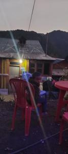 a boy sitting in a red chair with a bat at Rara Sunrise Hotel in Chautha