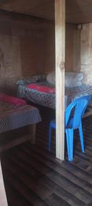 a blue chair in a room with two beds at Rara Sunrise Hotel in Chautha