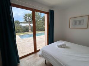 a bedroom with a bed and a sliding glass door at Vivez Cala Morell! in Cala Morell +35 photos