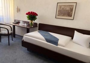 a bedroom with a bed and a table with a vase of flowers at Hotel Goldener Adler in Bautzen