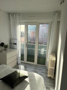 a white bedroom with a bed and a large window at DaxLodge T2 Sotf in Dax