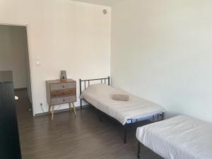 two beds in a room with a dresser and a table at Business Apparts Caudry in Caudry