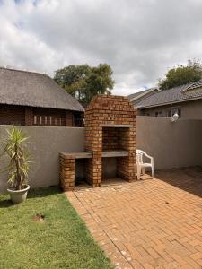 a brick patio with a bench and a brick wall at On Smook in Zeerust