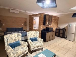 a bedroom with a bed and two chairs and a kitchen at On Smook in Zeerust