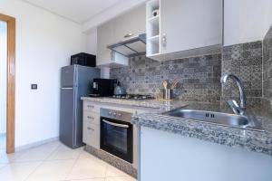 a kitchen with a sink and a refrigerator at Blue Waves 2 Bedrooms with Pool in Bouznika +17 photos