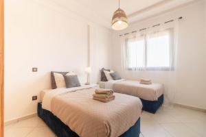 two beds in a room with white walls and a window at Blue Waves 2 Bedrooms with Pool in Bouznika