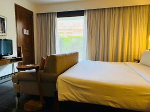 a hotel room with a bed and a chair and a window at RAAS Jodhpur in Jodhpur