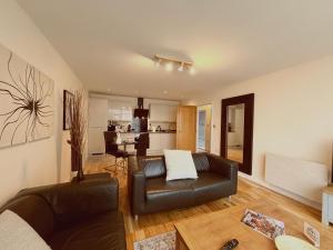 a living room with a leather couch and a kitchen at Cardiff City Center - FREE On-Site Parking in Cardiff