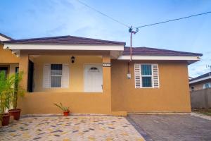 a yellow house with a white door at Colbeck sunshine oasis in Old Harbour
