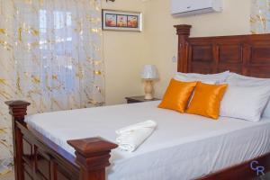 a bedroom with a bed with orange and white pillows at Colbeck sunshine oasis in Old Harbour +22 photos