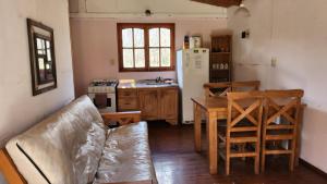 a kitchen with a couch and a table and a refrigerator at Cabaña La Mechita con jacuzzi privado in Estación Delta