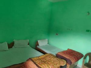 two beds in a room with green walls at Kedar Kunj in Phata